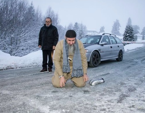 Mullah Krekar rukoilemassa jäisellä tiellä sen jälkeen, kun hänet oli vapautettu norjalaisesta vankilasta vuonna 2015. EPA/AOP
