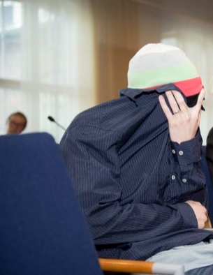 Epäilty surmaaja saapui saliin käsi tiukasti kasvoillaan. Kuva Minna Jalovaara
