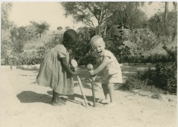 Suomalaisten lähetystöntekijöiden lapsi ja paikallinen lapsi leikkivät heittonuijilla Ambomaalla, nykyisen Namibian alueella. Kuva on otettu vuosien 1910 ja 1930 välillä.