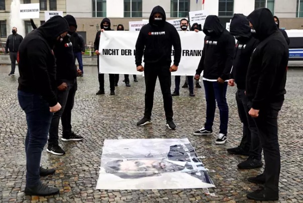 Muslimimielenosoittajat katsoivat kadulla olevaa Emmanuel Macronin kuvaa Berliinissä perjantaina.­KUVA: MICHELE TANTUSSI / REUTERS