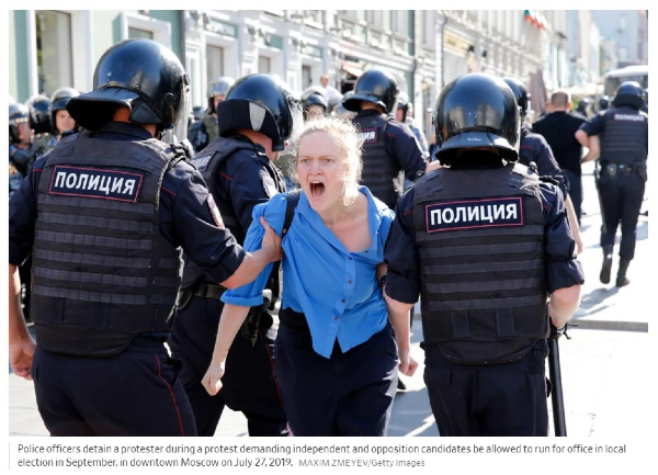 Venäläiset poliisit kuljettavat vihaista naista.jpg