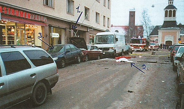 Isokatu Perämiehenkadun suuntaan. 1. Räjähdysalue. 2. Uhri. 3. Peugeot ja Volvo-henkilöautot sekä Mercedes-Benz -pakettiauto.jpg