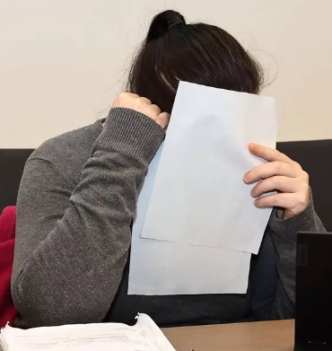 Taposta syytetty nainen peitteli kasvojaan paperilapulla käräjäoikeudessa. Kuva Tomi Natri.