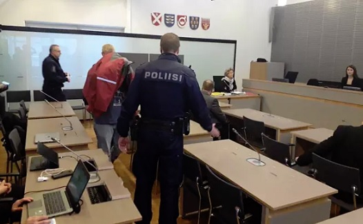 Poliisit saattoivat takin alla piilotelleen syytetyn käräjäsaliin Hyvinkäällä tiistaiaamuna. (KUVA: JUHO JOKINEN / HS)